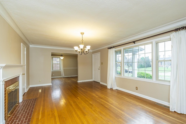 unfurnished living room featuring hardwood / wood-style flooring, crown molding, a textured ceiling, and a notable chandelier