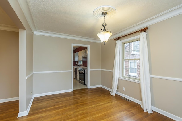 unfurnished dining area featuring hardwood / wood-style floors, crown molding, and sink