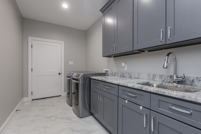 clothes washing area with washer and dryer, cabinets, and sink