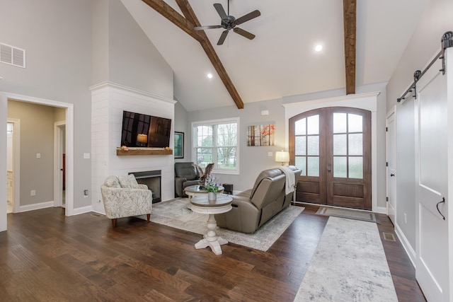 living room with beamed ceiling, french doors, dark hardwood / wood-style flooring, and a barn door