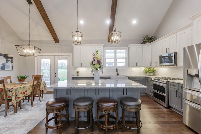 kitchen with stainless steel appliances, a kitchen island, hanging light fixtures, and white cabinetry