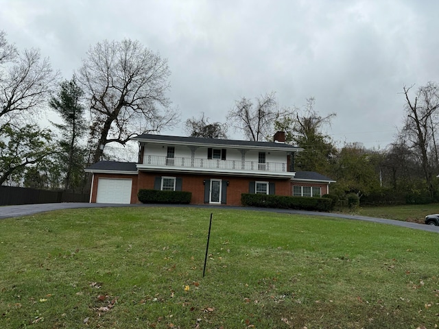 view of front of house featuring a front yard, a balcony, and a garage