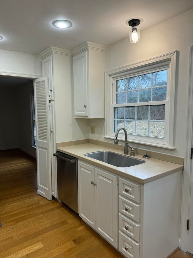 kitchen featuring stainless steel dishwasher, white cabinets, sink, and light hardwood / wood-style flooring