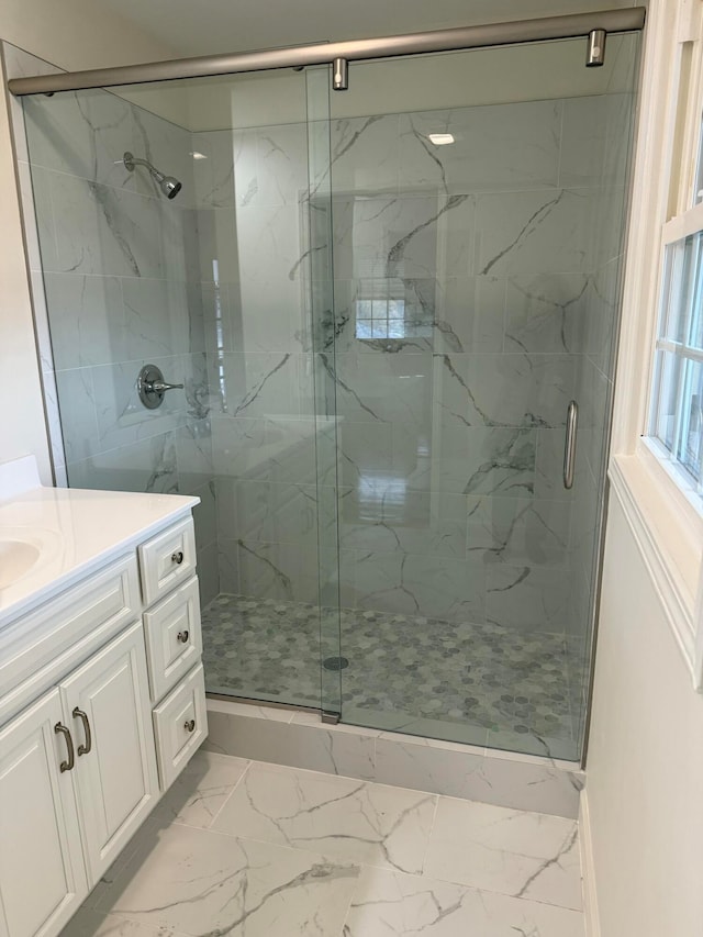 bathroom featuring a shower with door and vanity