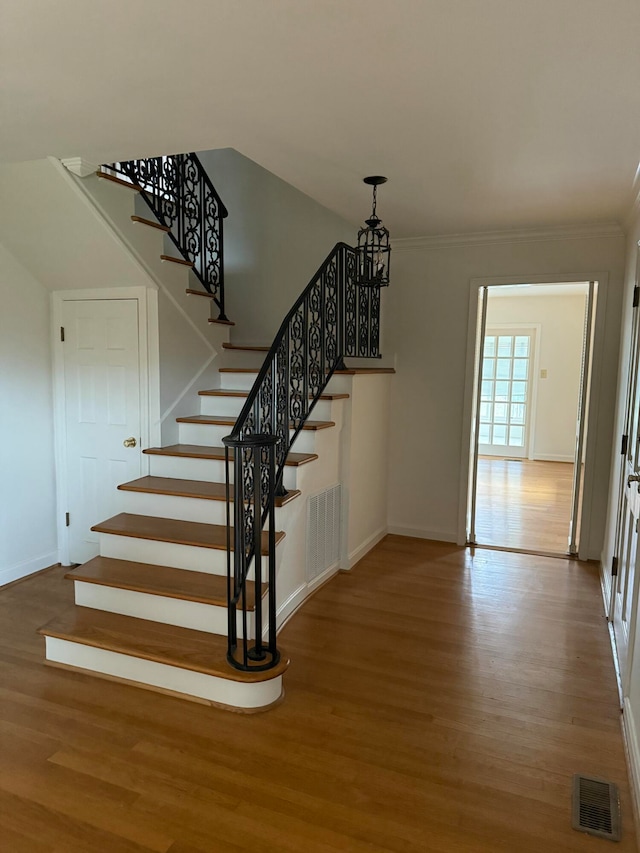 staircase featuring hardwood / wood-style flooring and ornamental molding