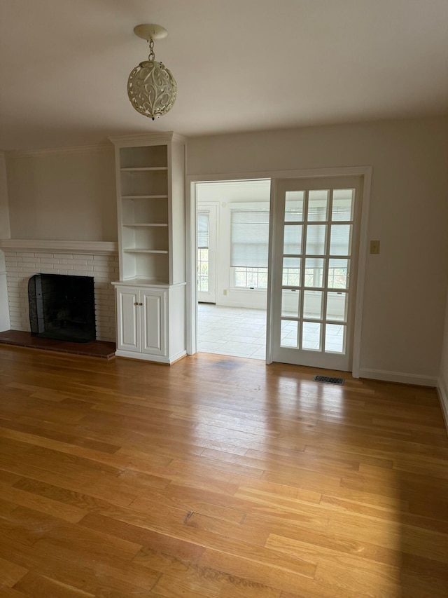 unfurnished living room featuring light wood-type flooring and a brick fireplace