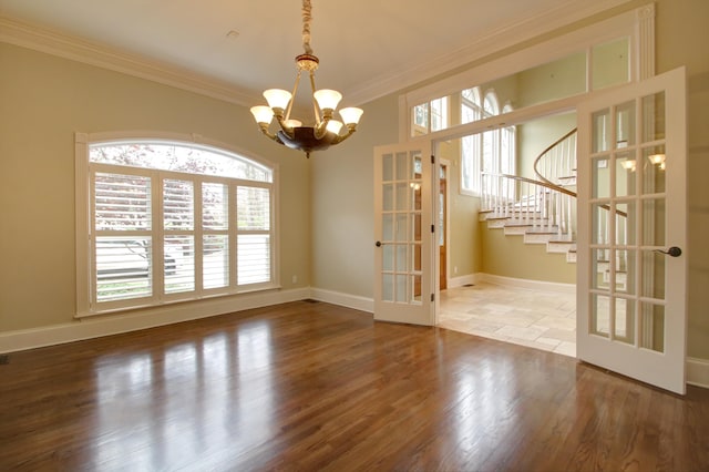 unfurnished dining area featuring wood-type flooring, crown molding, and french doors