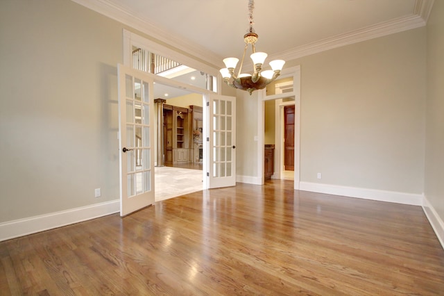 unfurnished dining area featuring french doors, a notable chandelier, crown molding, and hardwood / wood-style floors