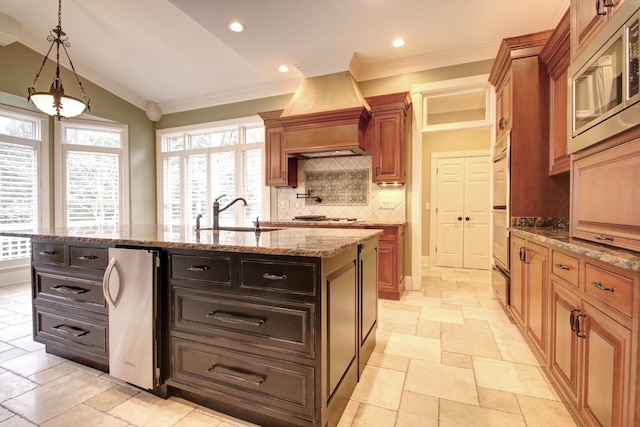 kitchen with premium range hood, a kitchen island with sink, sink, decorative backsplash, and stainless steel appliances