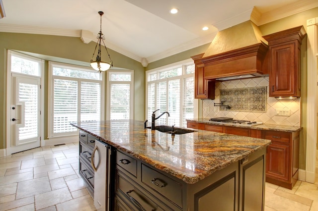 kitchen with light stone countertops, custom range hood, sink, a center island with sink, and lofted ceiling