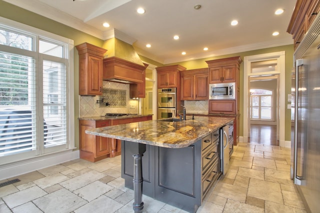 kitchen featuring decorative backsplash, a center island with sink, light stone countertops, and appliances with stainless steel finishes