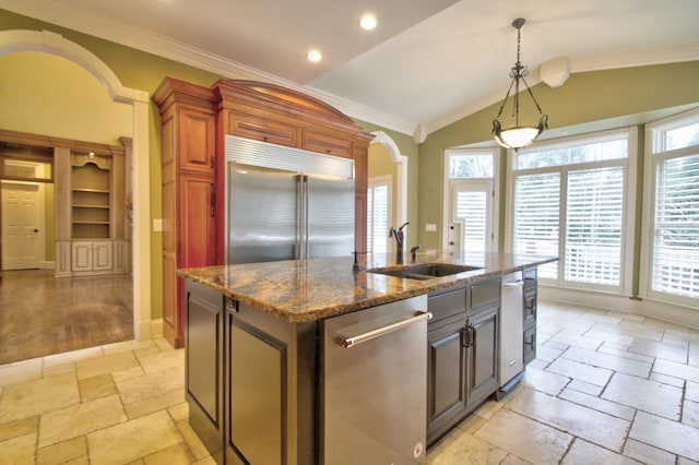 kitchen with sink, hanging light fixtures, stainless steel appliances, an island with sink, and vaulted ceiling