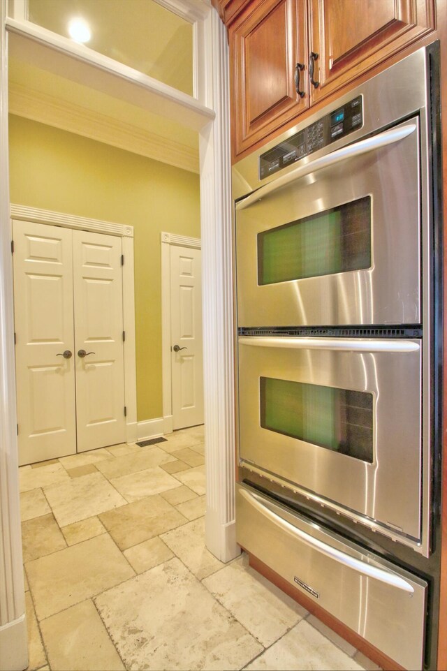 kitchen featuring crown molding, dark stone countertops, stainless steel appliances, and a large island with sink