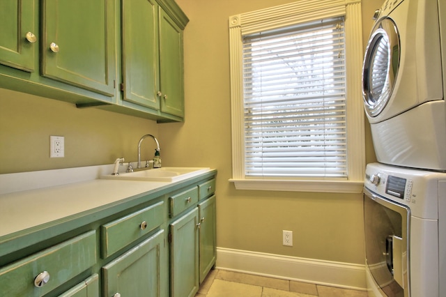 laundry area with stacked washer / drying machine, light tile patterned flooring, cabinets, and sink