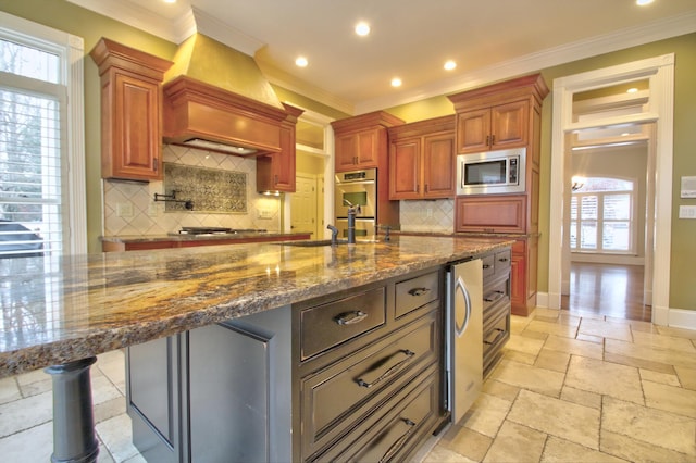 kitchen featuring dark stone counters, stainless steel appliances, and a large island with sink