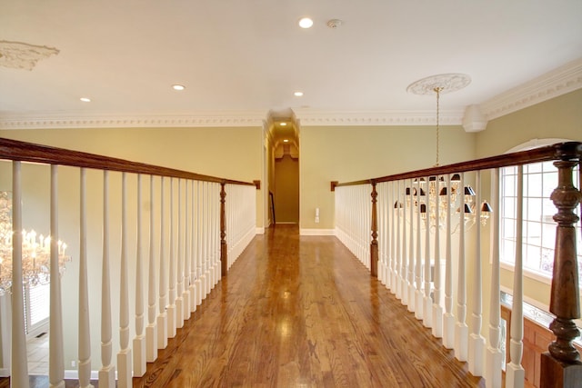 corridor with crown molding, hardwood / wood-style floors, and a notable chandelier