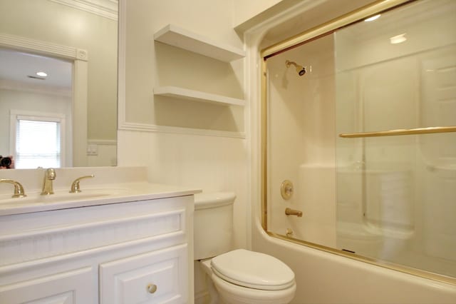 full bathroom featuring bath / shower combo with glass door, ornamental molding, vanity, and toilet