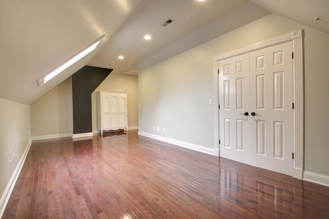 additional living space featuring lofted ceiling with skylight and dark hardwood / wood-style floors