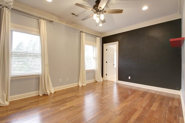 spare room with ceiling fan, crown molding, wood-type flooring, and a healthy amount of sunlight