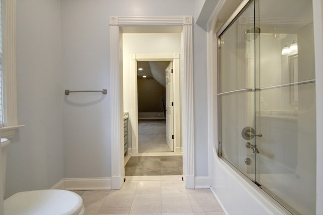 bathroom featuring tile patterned flooring, toilet, and combined bath / shower with glass door