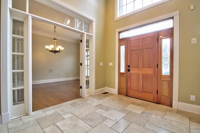 foyer featuring a wealth of natural light, crown molding, light hardwood / wood-style flooring, and a notable chandelier