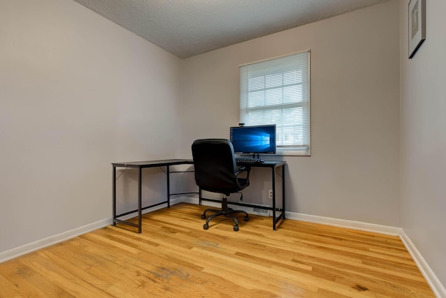 office area with light hardwood / wood-style floors and a textured ceiling