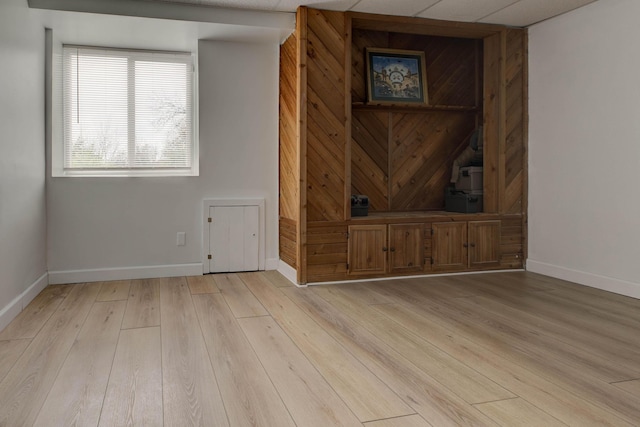 unfurnished room featuring light wood-type flooring and a paneled ceiling