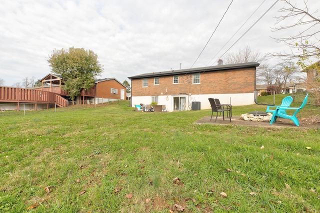 rear view of house with a yard, an outdoor fire pit, cooling unit, and a wooden deck