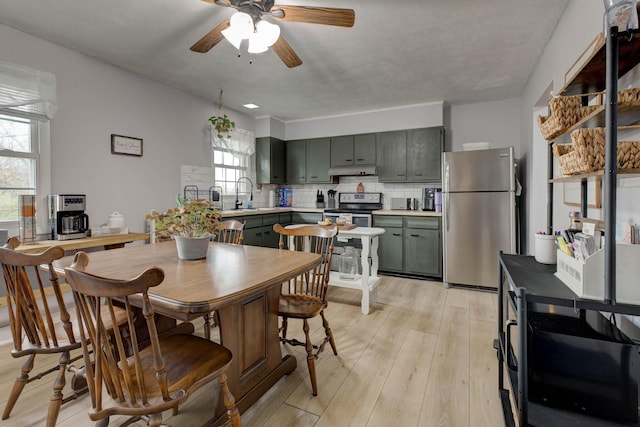 dining room featuring a textured ceiling, ceiling fan, light hardwood / wood-style floors, and sink