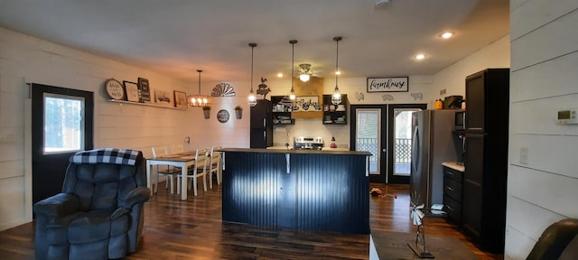 kitchen with stainless steel fridge, a kitchen breakfast bar, dark hardwood / wood-style flooring, stove, and decorative light fixtures