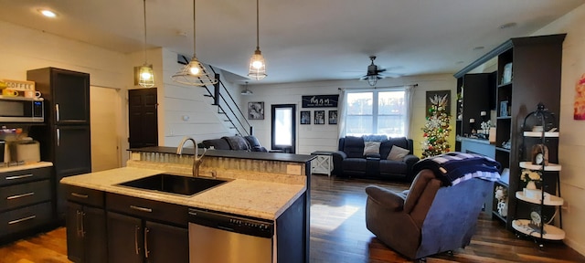 kitchen with stainless steel appliances, ceiling fan, a kitchen island with sink, dark wood-type flooring, and sink