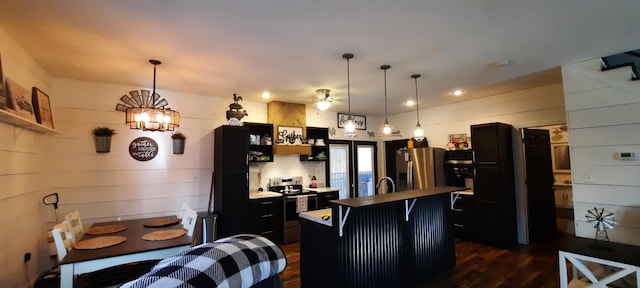 kitchen featuring a center island with sink, a kitchen breakfast bar, stainless steel appliances, and decorative light fixtures