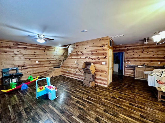 playroom with wooden walls, ceiling fan, and dark hardwood / wood-style floors