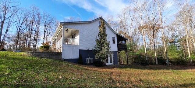 view of side of home featuring a yard and a balcony