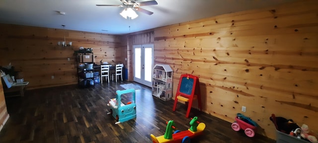 game room with dark hardwood / wood-style floors, ceiling fan, wooden walls, and french doors