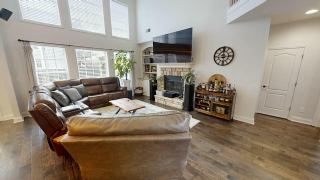 living room featuring a fireplace, a towering ceiling, and dark hardwood / wood-style floors