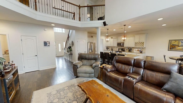 living room featuring a high ceiling and dark wood-type flooring