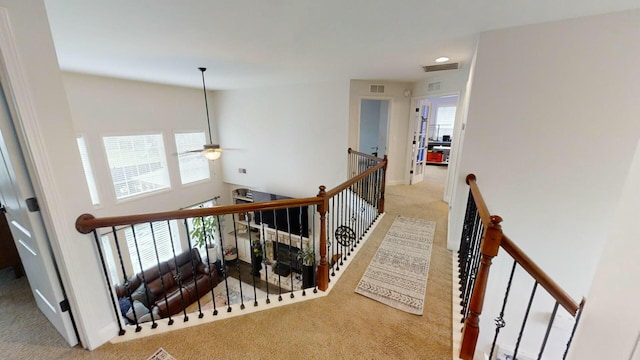 stairs with ceiling fan and carpet floors