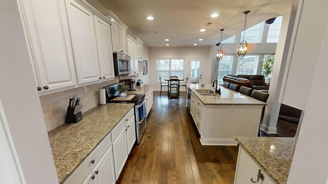 kitchen with a kitchen island with sink, white cabinets, light stone countertops, dark hardwood / wood-style flooring, and stainless steel appliances