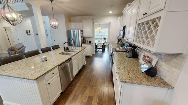 kitchen with a center island with sink, pendant lighting, white cabinets, and stainless steel appliances