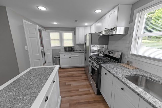 kitchen featuring white cabinets, stainless steel gas stove, hardwood / wood-style flooring, and a wealth of natural light