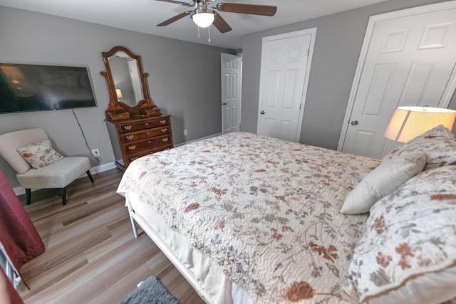 bedroom with two closets, light hardwood / wood-style flooring, and ceiling fan