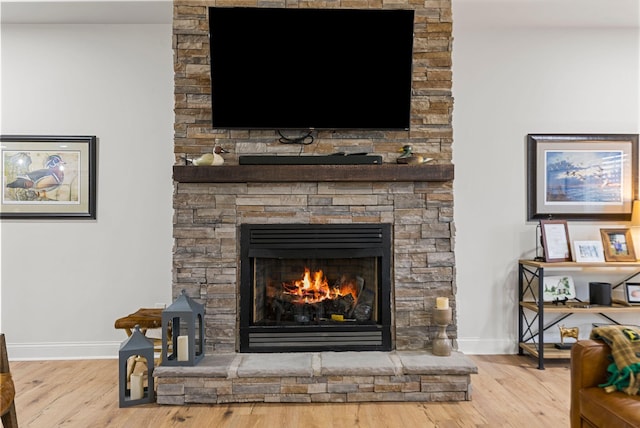 interior details featuring a stone fireplace, wood finished floors, and baseboards