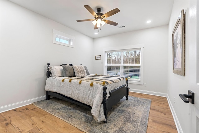 bedroom featuring baseboards, multiple windows, visible vents, and wood finished floors