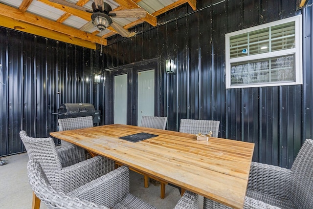 dining area featuring ceiling fan, beam ceiling, and wooden walls