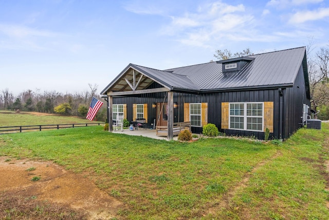 view of front of property with board and batten siding, a front yard, a patio area, and metal roof