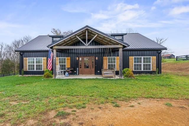 back of property with board and batten siding, a yard, a patio area, and metal roof