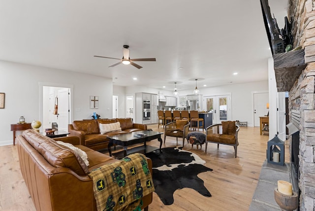 living area featuring light wood-style floors, recessed lighting, ceiling fan, and a stone fireplace