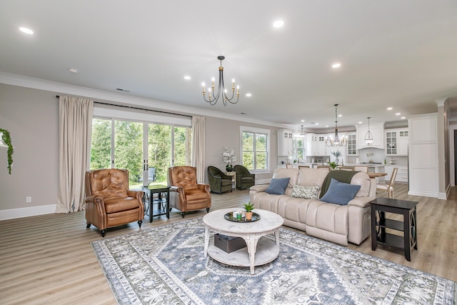 living room with a healthy amount of sunlight, light wood-type flooring, an inviting chandelier, and ornamental molding