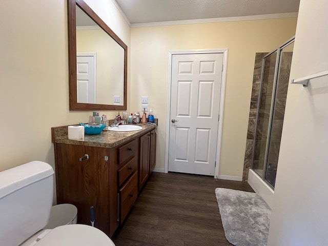 bathroom featuring vanity, toilet, wood-type flooring, and ornamental molding